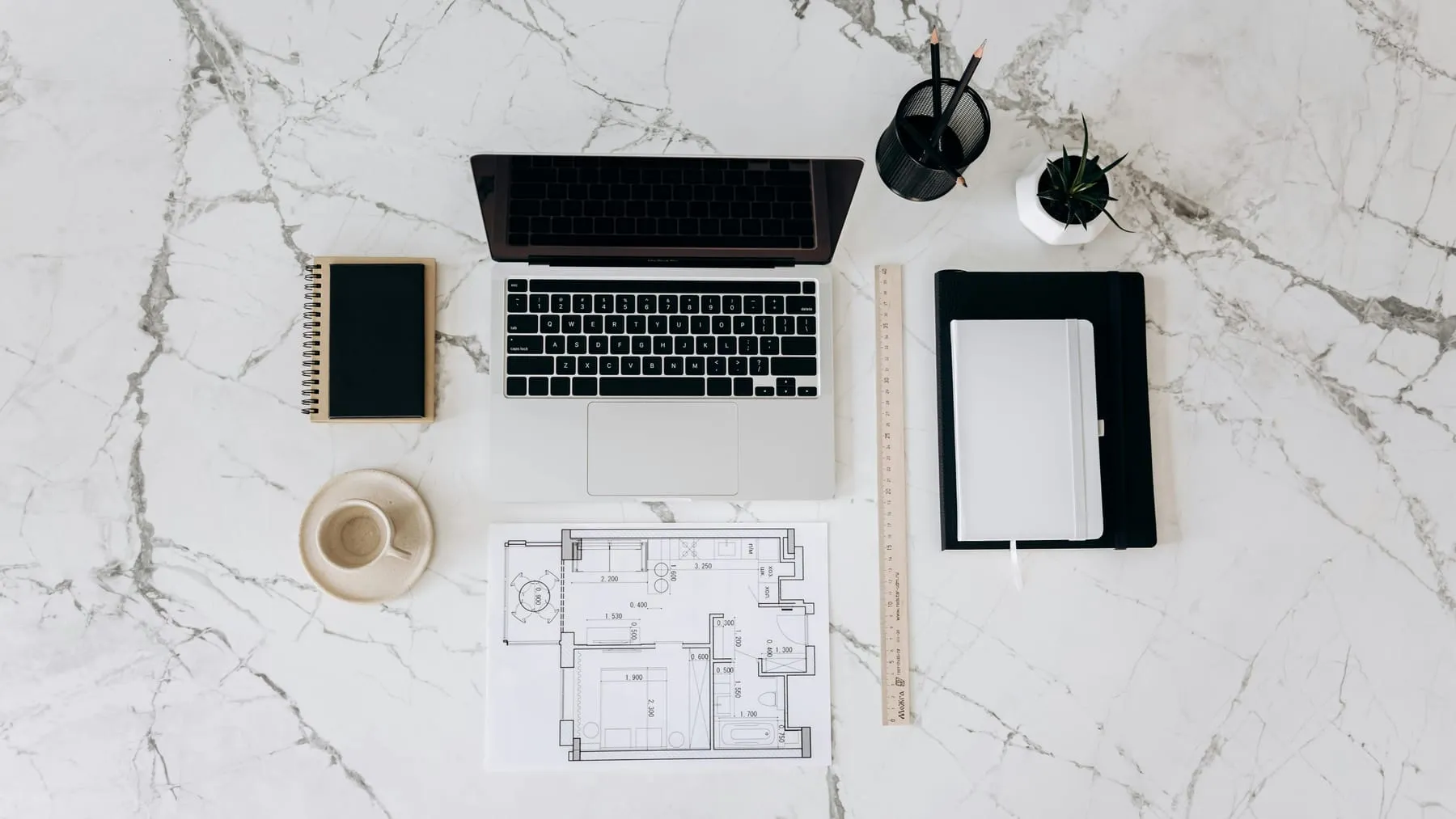 An organised desk with a laptop, notebook, and papers laid out neatly
