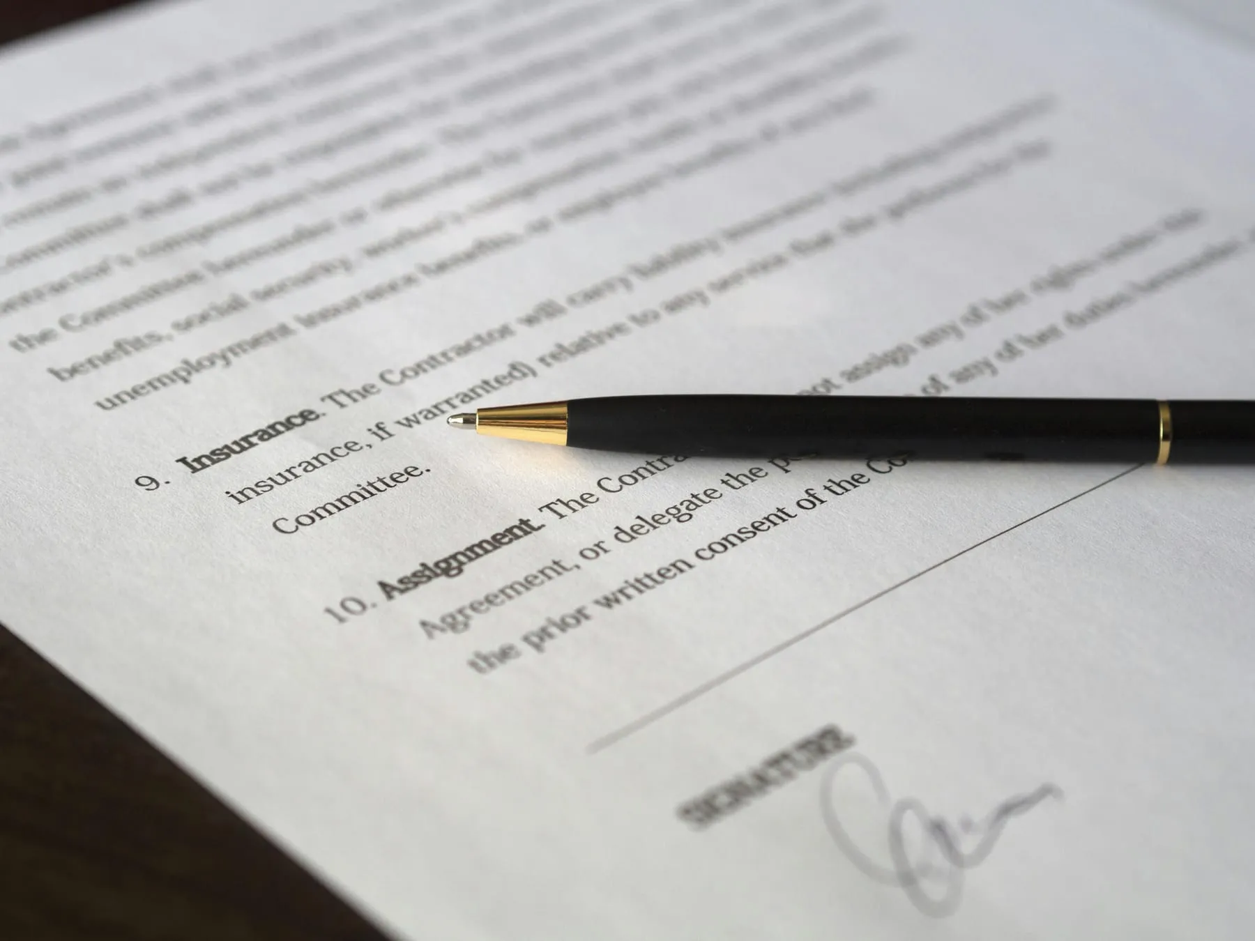 A pen resting on a commercial contract, beside a signature line